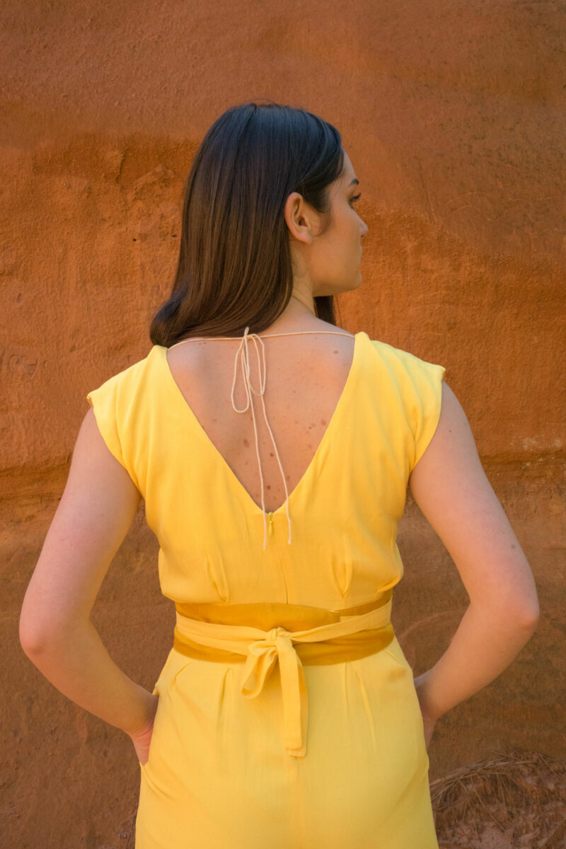 Woman from back wearing yellow trouser jumpsuit with silk belt