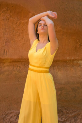 Woman wearing yellow trouser jumpsuit with silk belt