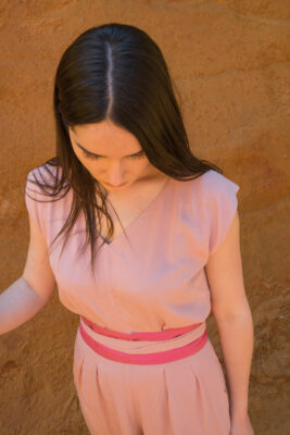 Woman wearing pink jumpsuit silk belt